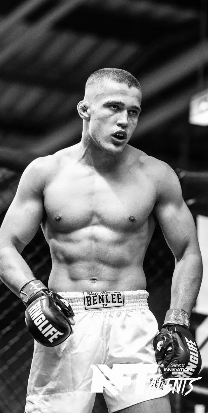 Moritz Barth mit freiem Oberkörper, MMA-Handschuhen und weißen Shorts im Käfig bei NFT Talents 2.